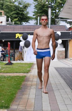 Timisoara, Romanya, 24 Haziran 2018 'de Opera Moda Fuarı' nda bir erkek model, ihtiraslı bir şekilde hayır işi için yapılan zarif mavi mayo sunar.