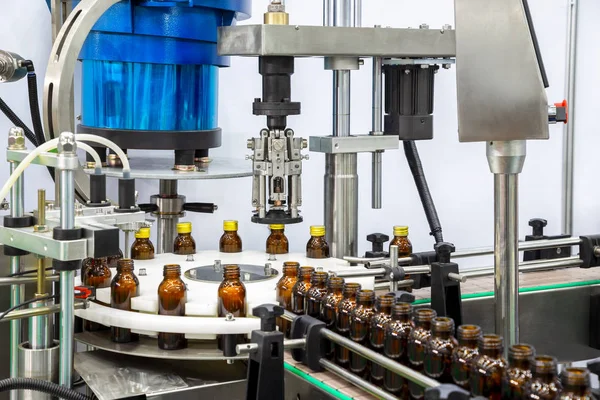 Sterile bottles on the production line conveyor of the pharmaceutical industry. Machine for liquid drugs glassware bottling.