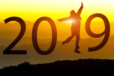 Gün batımı arka planda yeni yıl 2019 konseptiyle tepede atlamayı özgürlük mutlu genç kadın silüeti.