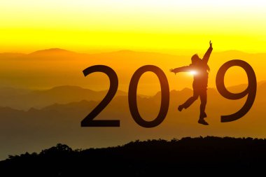 Gün batımı arka planda yeni yıl 2019 konseptiyle tepede atlamayı özgürlük mutlu genç kadın silüeti.