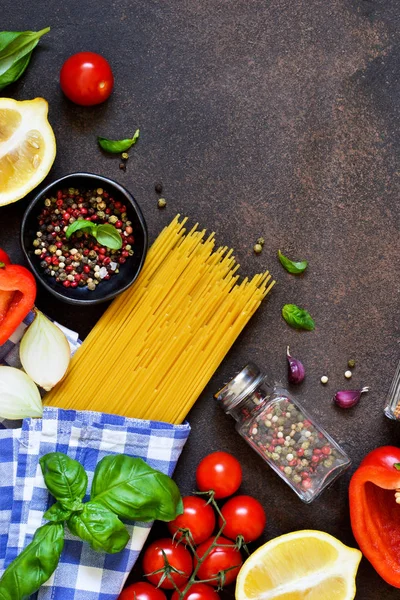 İtalyan yemeği arka plan. Makarna yemek pişirmek için malzemeler: spagetti, domates, fesleğen, karabiber karanlık bir beton zemin üzerine.