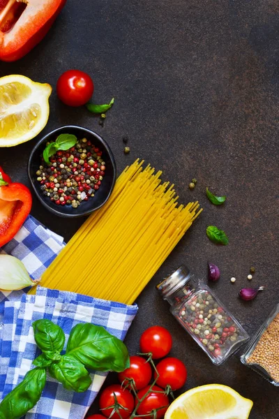 İtalyan yemeği arka plan. Makarna yemek pişirmek için malzemeler: spagetti, domates, fesleğen, karabiber karanlık bir beton zemin üzerine.