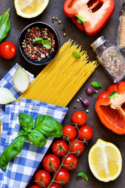 İtalyan yemeği arka plan. Makarna yemek pişirmek için malzemeler: spagetti, domates, fesleğen, karabiber karanlık bir beton zemin üzerine.