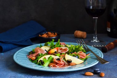 Jamon, armut, yaban mersini ve badem salatası. Bir bardak soğuk, kırmızı şarap. İncelik.