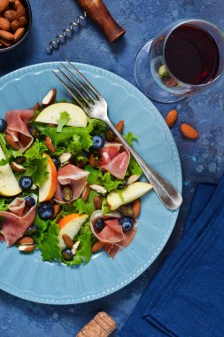 Jamon, armut, yaban mersini ve badem salatası. Bir bardak soğuk, kırmızı şarap. İncelik.