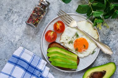 Klasik kahvaltı: avokado, yumurta ve sebze bir beton zemin üzerine tost.