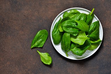 Bir beton zemin üzerine bir tabak içinde taze, Genç ıspanak. Organik gıda.