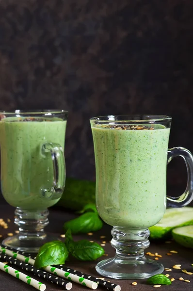 Green smoothies with avocado, cucumber, basil and granola on a dark stony background. Dietary drink.