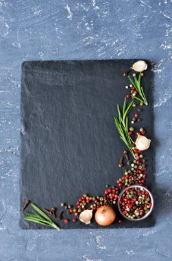 Siyah, kırmızı ve beyaz biber, biberiye ve siyah arduvaz arka planda sarımsak.