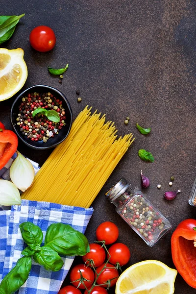 İtalyan yemeği arka plan. Makarna yemek pişirmek için malzemeler: spagetti, domates, fesleğen, karabiber karanlık bir beton zemin üzerine.