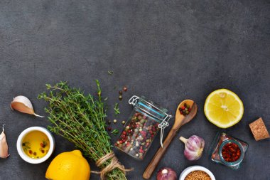 Marine için farklı baharatlar: biberiye, kekik, biber, sarımsak, limon ve zeytin yağı siyah bir arka plan. Üstten görünüm.