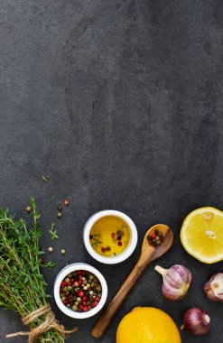 Marine için farklı baharatlar: biberiye, kekik, biber, sarımsak, limon ve zeytin yağı siyah bir arka plan. Üstten görünüm.