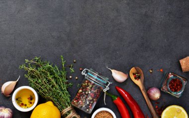 Marine için farklı baharatlar: biberiye, kekik, biber, sarımsak, limon ve zeytin yağı siyah bir arka plan. Üstten görünüm.