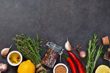 Marine için farklı baharatlar: biberiye, kekik, biber, sarımsak, limon ve zeytin yağı siyah bir arka plan. Üstten görünüm.