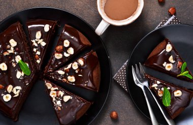 Sıcak çikolata sosu ve karanlık, beton zemin üzerine kızarmış fındık ile çikolatalı kek.