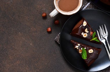 Sıcak çikolata sosu ve karanlık, beton zemin üzerine kızarmış fındık ile çikolatalı kek.