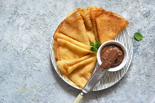 Свежие блинчики с шоколадной пастой и бананами на бетонной пабе — стоковое фото