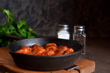 Bir deto üzerinde bir Pan içinde biber baharatlar ile domates sosu köftesi