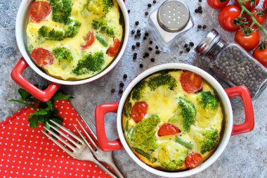 Casserole with broccoli and tomatoes on a concrete background. clipart