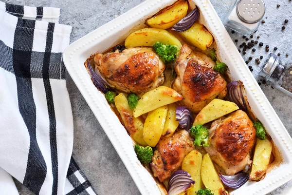 Hot spicy chicken with potatoes and broccoli baked. Concrete bac