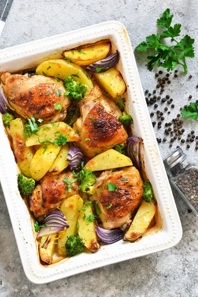 Hot spicy chicken with potatoes and broccoli baked. Concrete bac