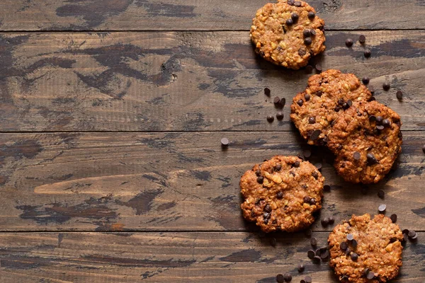 Galletas de avena con gotas de chocolate sobre un fondo de madera . — Foto de Stock