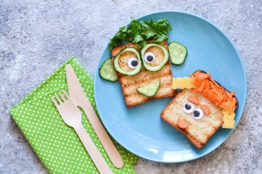 Komik yüzler- çocuk için öğle yemeği. Sebzeli sandviç. 