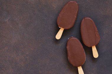 Çikolatalı dondurma. Beton arka planda buzlu şeker. Üstte görüntü.