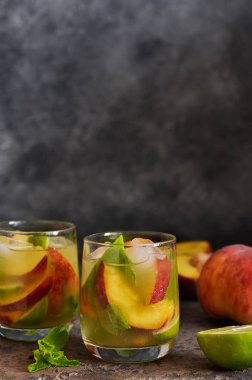 Koyu beton arka plan üzerinde şeftali ve kireç ile soğuk limonata.