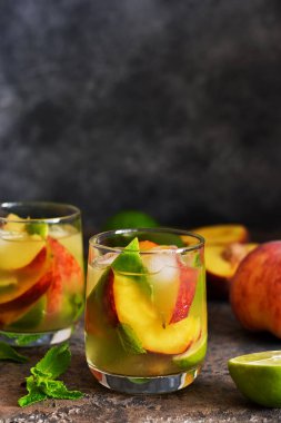 Koyu beton arka plan üzerinde şeftali ve kireç ile soğuk limonata.