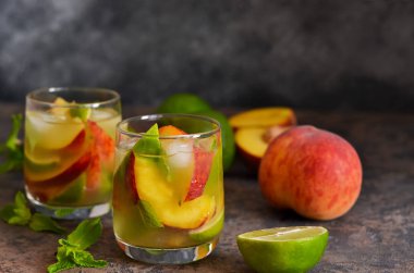 Koyu beton arka plan üzerinde şeftali ve kireç ile soğuk limonata.