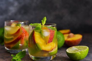Koyu beton arka plan üzerinde şeftali ve kireç ile soğuk limonata.