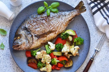 Güzel bir tabakta sebze ve biberiye ile Pişmiş dorado.