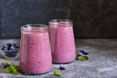 Mutfak masasında yaban mersini olan mor smoothie'ler. Detoks beni