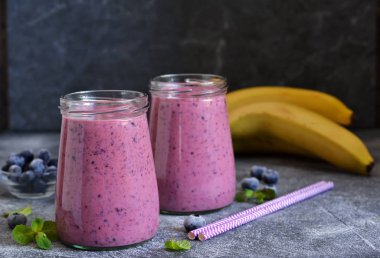 Mutfak masasında yaban mersini olan mor smoothie'ler. Detoks