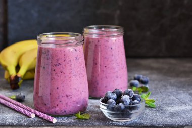 Mutfak masasında yaban mersini olan mor smoothie'ler. Detoks beni