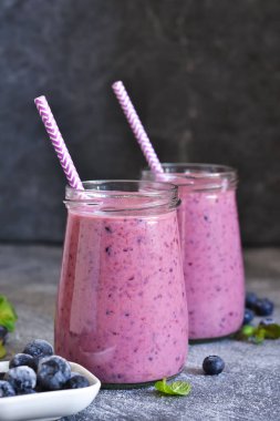 Mutfak masasında yaban mersini olan mor smoothie'ler. Detoks
