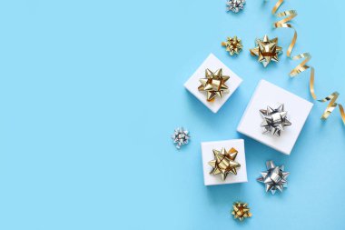 Mavi arka planda bir doğum günü için düz kompozisyon. Altın yaylı şık hediyeler..