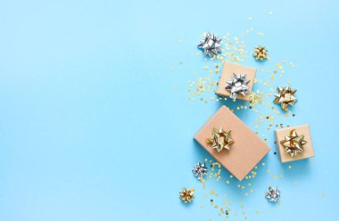 Mavi arka planda bir doğum günü için düz kompozisyon. Altın yaylı şık hediyeler..