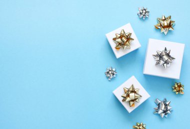 Mavi arka planda bir doğum günü için düz kompozisyon. Altın yaylı şık hediyeler..