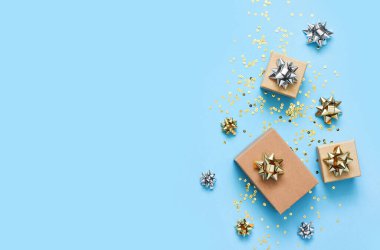 Mavi arka planda bir doğum günü için düz kompozisyon. Altın yaylı şık hediyeler..