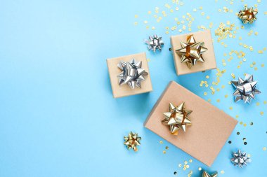 Mavi arka planda bir doğum günü için düz kompozisyon. Altın yaylı şık hediyeler..