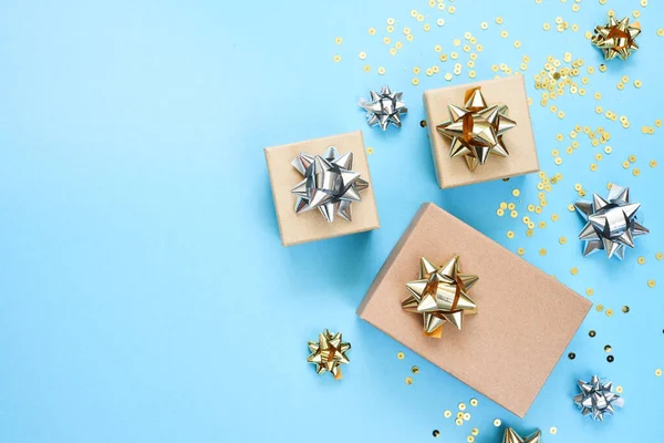 Mavi arka planda bir doğum günü için düz kompozisyon. Altın yaylı şık hediyeler..