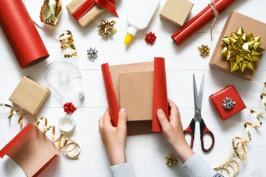 Bir çocuğun elleri hediyeyi paketliyor. Yukarıdan bak. Adım adım fotoğraf. Birinci adım..