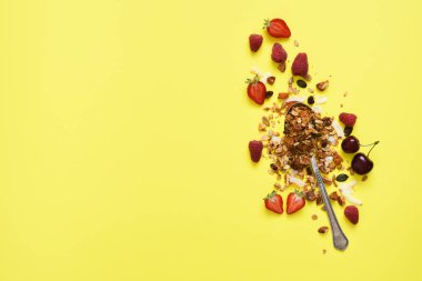 Sarı arka planda fındık ve böğürtlenli granola. Yukarıdan görüntüle.