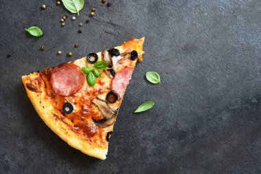 Siyah arka planda salamlı, mantarlı, zeytinli ve fesleğenli pizza dilimleri. Üst görünüm.
