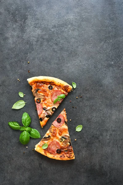 Siyah arka planda salamlı, mantarlı, zeytinli ve fesleğenli pizza dilimleri. Üst görünüm.