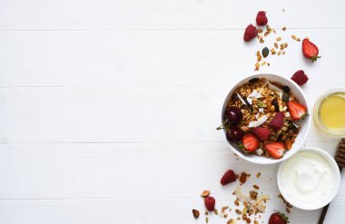 Klasik kahvaltı. Ballı tahıl gevreği, yoğurt ve beyaz ahşap arka planda böğürtlen. Yukarıdan görüntüle.