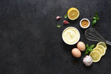 Siyah arka planda ev yapımı mayonez. Sos yapmak için gerekli malzemeler: yumurta, tereyağı, hardal.