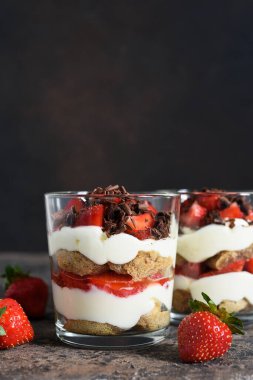Krem peynirli tatlı, çilek ve beton arka planda bir bardakta çikolata. Çilekli tiramisu..
